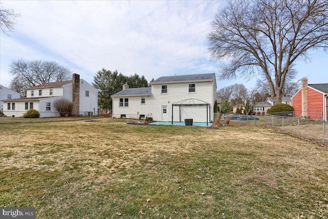 rear view of property with a patio, a lawn, an attached garage, and fence