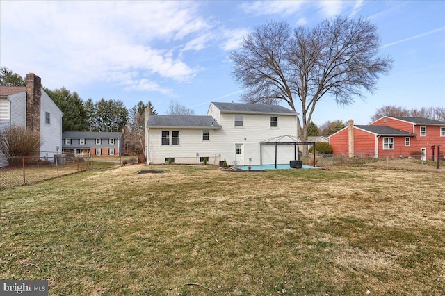 rear view of property featuring a garage, a lawn, and fence