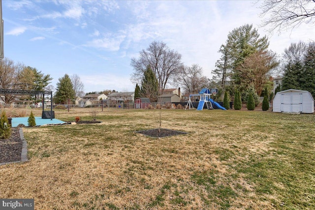 view of yard with an outbuilding, a storage shed, a playground, and fence