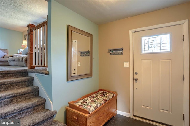 foyer featuring stairway, baseboards, and a textured ceiling