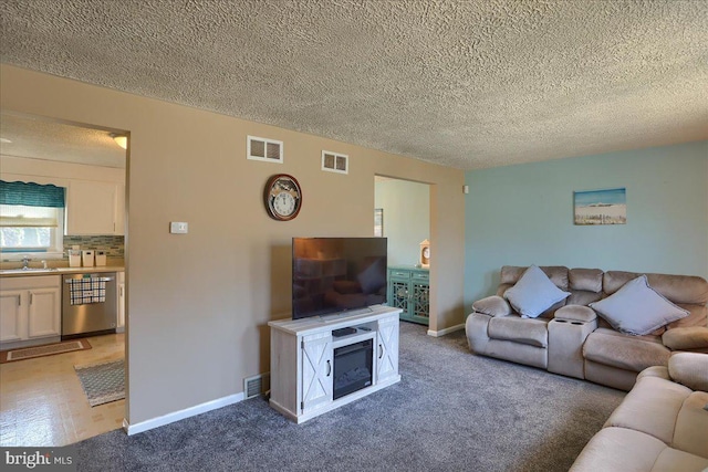 living room featuring visible vents, a textured ceiling, carpet, and baseboards