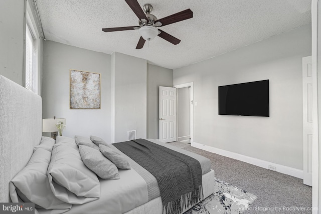 carpeted bedroom featuring ceiling fan, visible vents, baseboards, and a textured ceiling