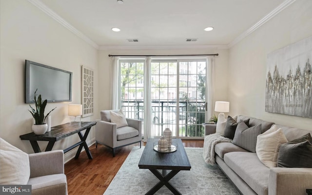 living room with visible vents, wood finished floors, and ornamental molding