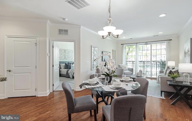 dining area featuring visible vents, a notable chandelier, wood finished floors, and ornamental molding