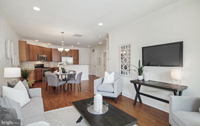 living area with a chandelier, visible vents, crown molding, and wood finished floors