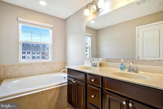 bathroom with double vanity, visible vents, a garden tub, and a sink