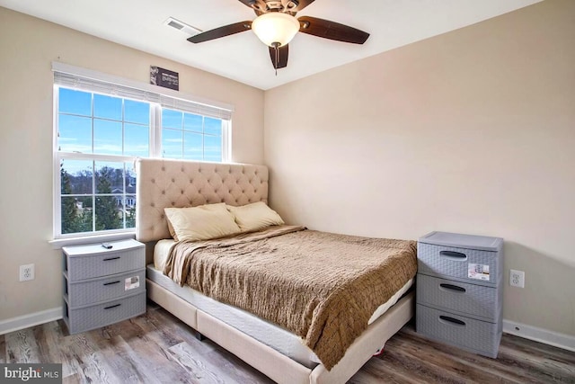 bedroom with wood finished floors, visible vents, and baseboards