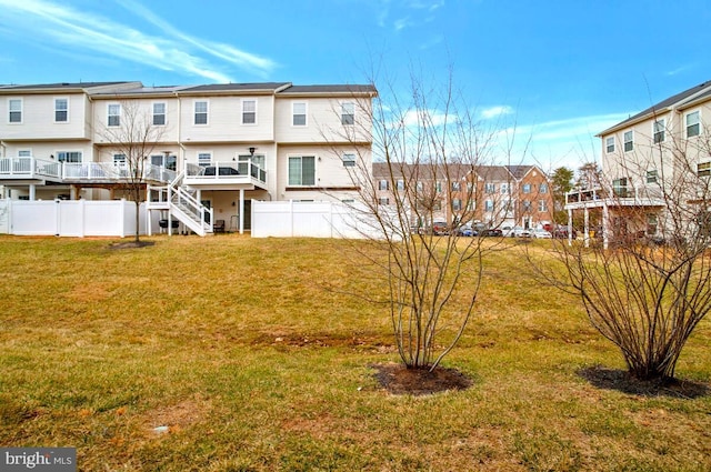 back of property featuring a deck, stairway, fence, and a lawn