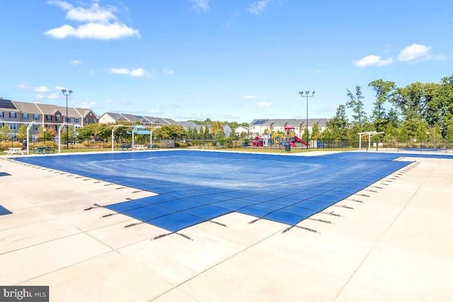 pool featuring a patio area, playground community, and fence