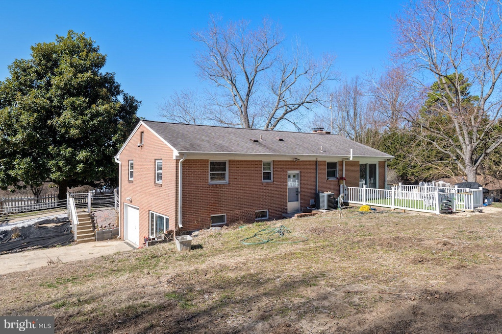 rear view of house with brick siding, fence, concrete driveway, cooling unit, and an attached garage