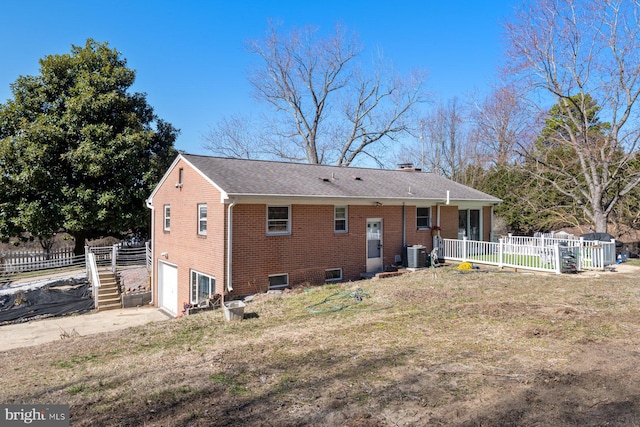 back of house with brick siding, fence, central AC unit, a chimney, and an attached garage