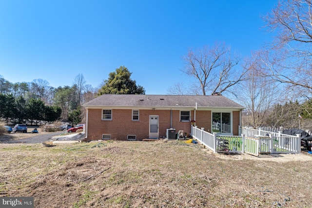 back of house with brick siding, central AC unit, and fence