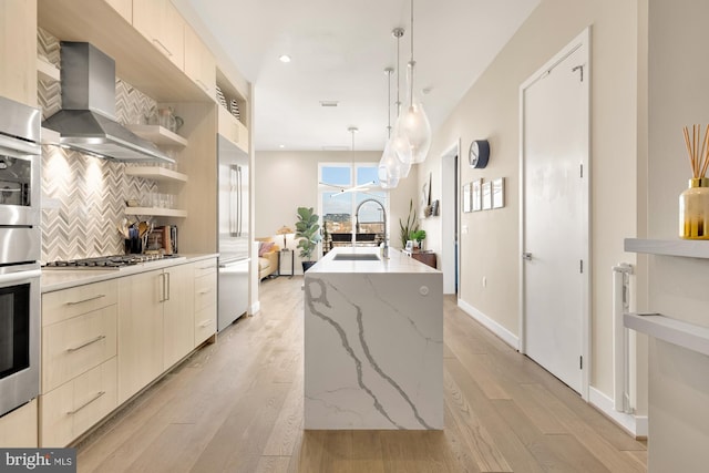 kitchen with wall chimney exhaust hood, modern cabinets, appliances with stainless steel finishes, and a sink