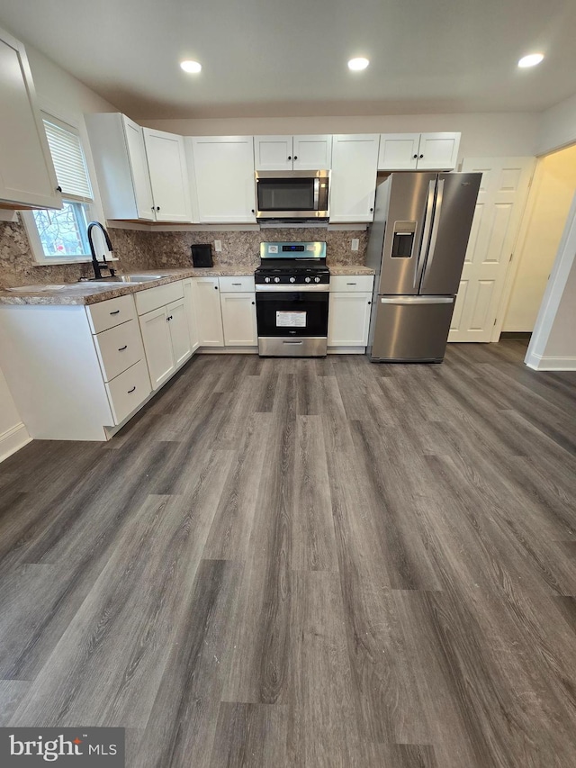 kitchen featuring a sink, tasteful backsplash, dark wood-style floors, white cabinetry, and appliances with stainless steel finishes