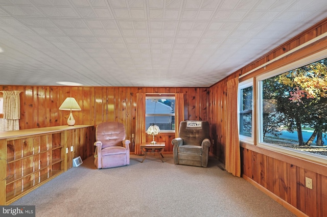 sitting room featuring visible vents, carpet floors, and wood walls