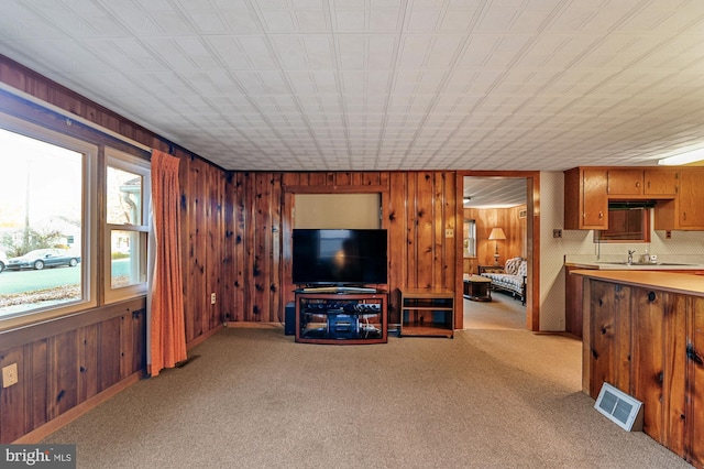 living area with light colored carpet, visible vents, and wood walls