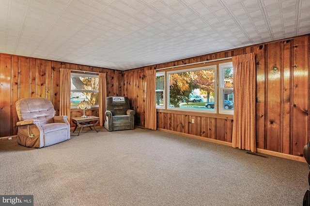 unfurnished room with visible vents, baseboards, wooden walls, and carpet flooring