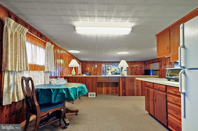 dining area featuring light carpet, visible vents, and wood walls