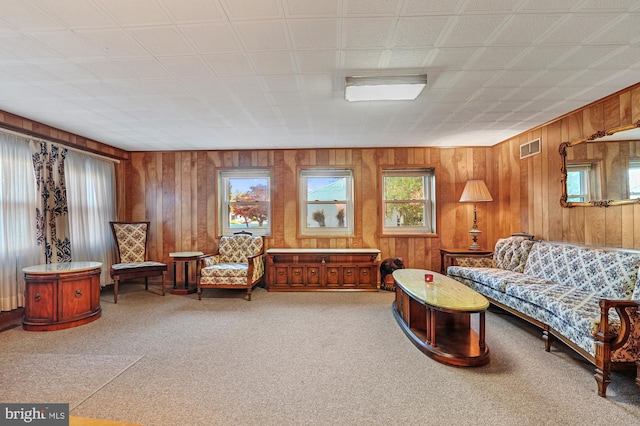 living room with visible vents, carpet floors, and wooden walls