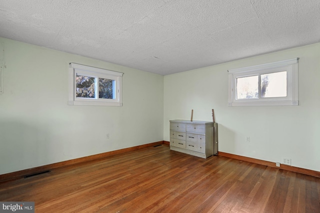 unfurnished bedroom featuring visible vents, wood finished floors, baseboards, and a textured ceiling