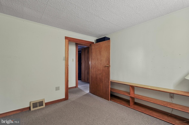 carpeted spare room featuring baseboards, visible vents, and a textured ceiling