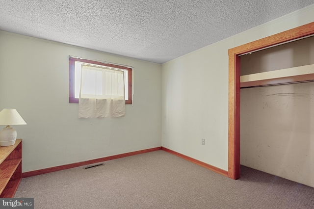 unfurnished bedroom featuring visible vents, a textured ceiling, a closet, carpet floors, and baseboards