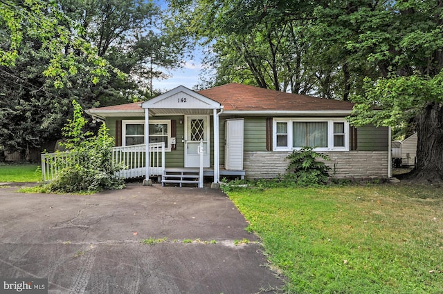 bungalow-style home featuring stone siding, covered porch, and a front yard