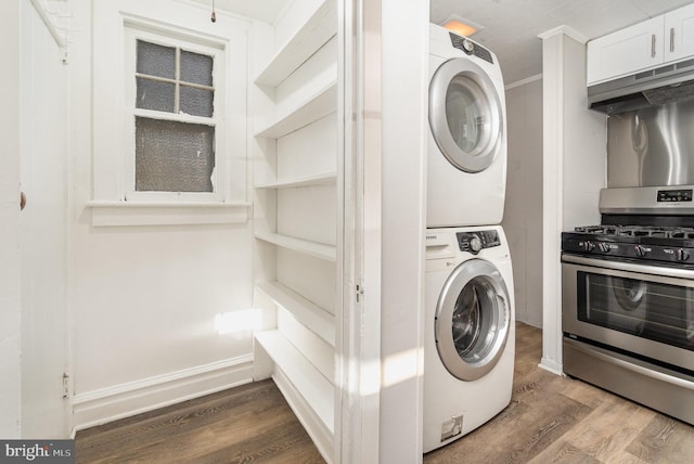 laundry room featuring dark wood-style floors, stacked washer / drying machine, and baseboards