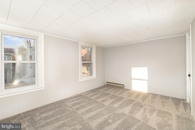 carpeted empty room featuring a baseboard heating unit and crown molding