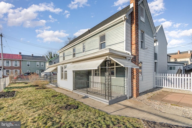 back of property featuring a chimney, a yard, and fence