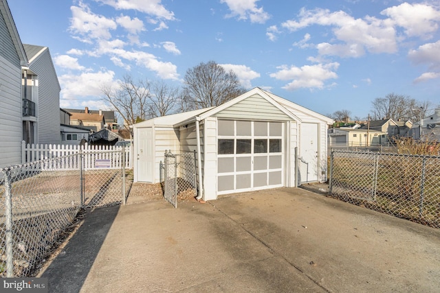 garage featuring a residential view, concrete driveway, and fence