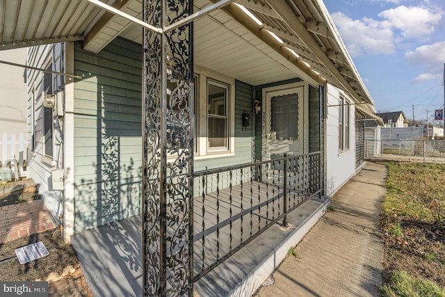 entrance to property featuring fence and covered porch