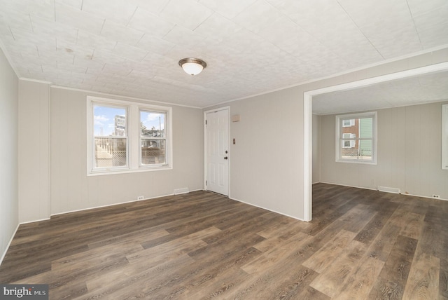 empty room with crown molding and wood finished floors