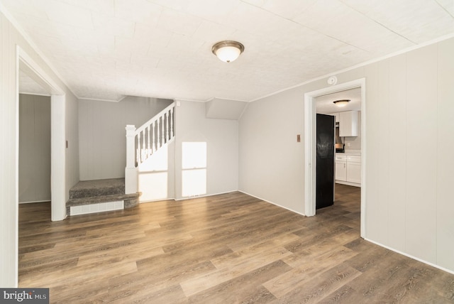 unfurnished living room with wood finished floors, stairs, and ornamental molding