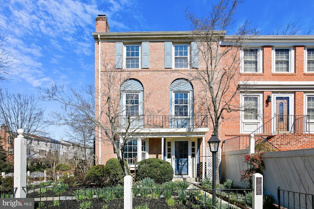 townhome / multi-family property with a fenced front yard, brick siding, and a chimney