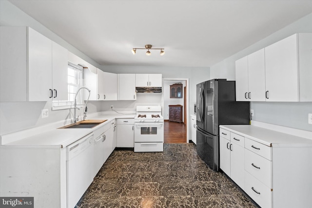 kitchen with white appliances, exhaust hood, light countertops, and a sink