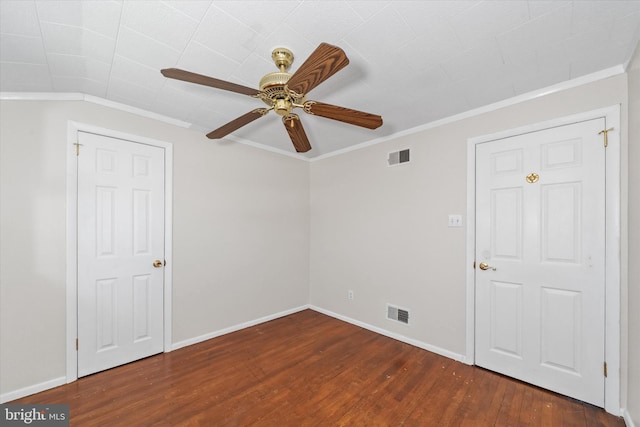 empty room featuring visible vents, crown molding, baseboards, and wood finished floors