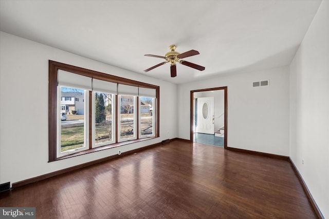 empty room featuring wood finished floors, visible vents, and baseboards