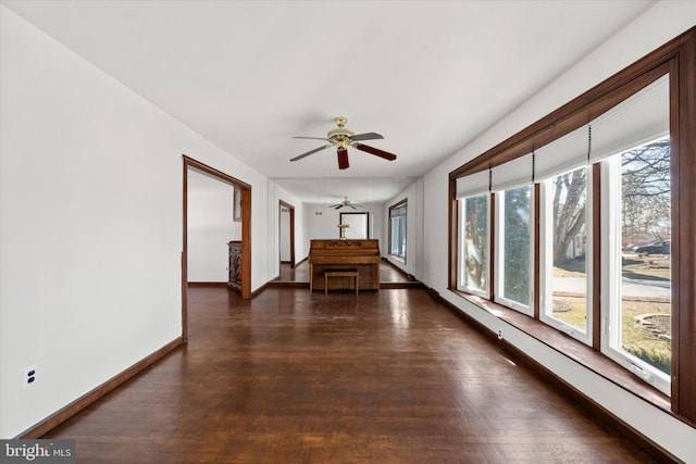 interior space featuring a ceiling fan, baseboards, and dark wood-style flooring