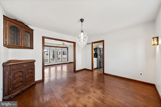 unfurnished dining area featuring dark wood-type flooring, a notable chandelier, visible vents, and baseboards