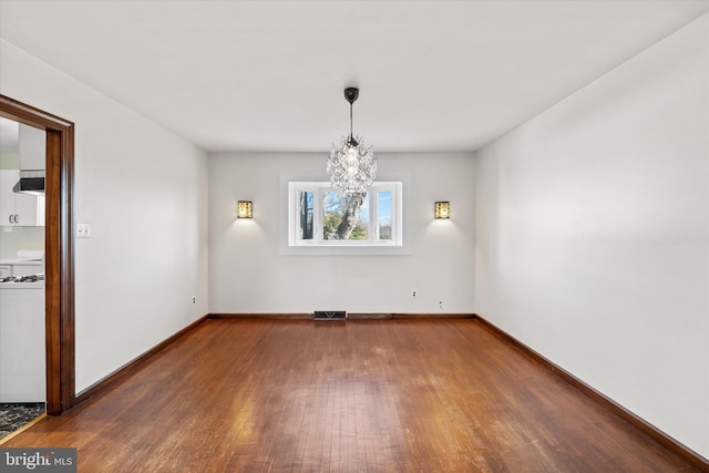 spare room featuring visible vents, an inviting chandelier, baseboards, and wood finished floors