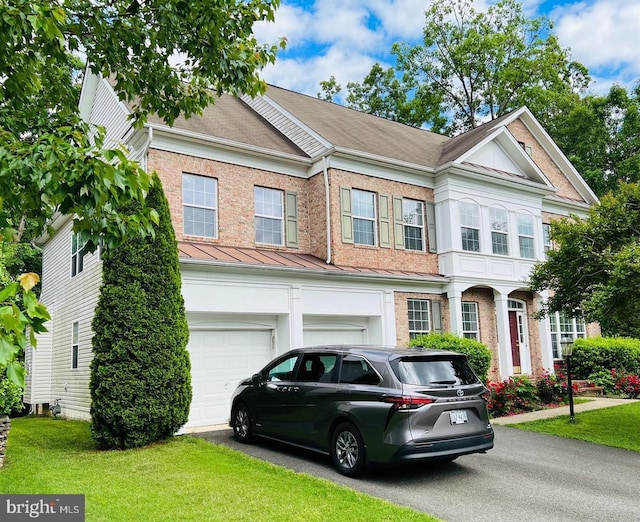 townhome / multi-family property with brick siding, driveway, a front lawn, and a garage