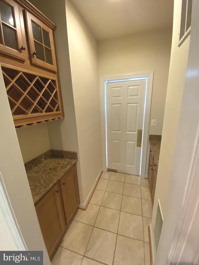 interior space with light tile patterned flooring, visible vents, a bar, and baseboards