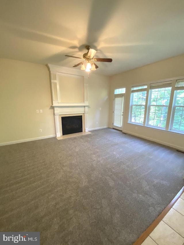 unfurnished living room featuring a fireplace with flush hearth, baseboards, carpet floors, and ceiling fan