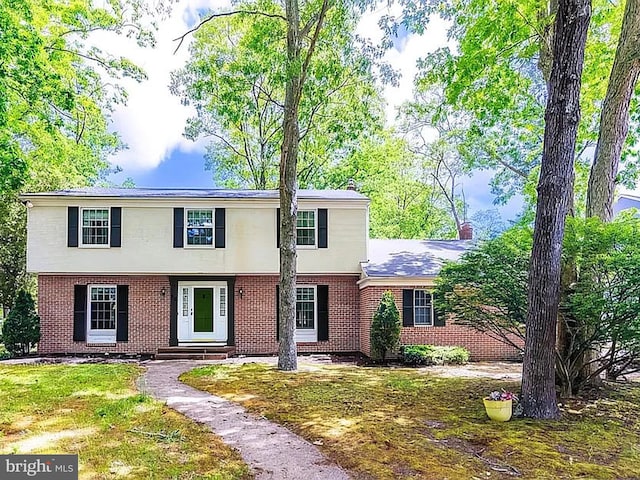 colonial inspired home featuring a front lawn and brick siding