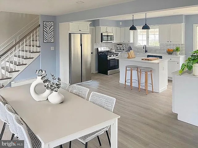 dining space featuring stairs and light wood finished floors