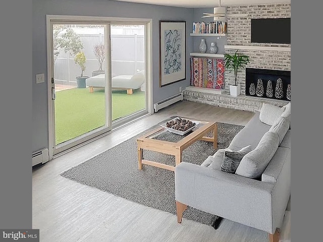 living room featuring baseboard heating, a fireplace, and wood finished floors