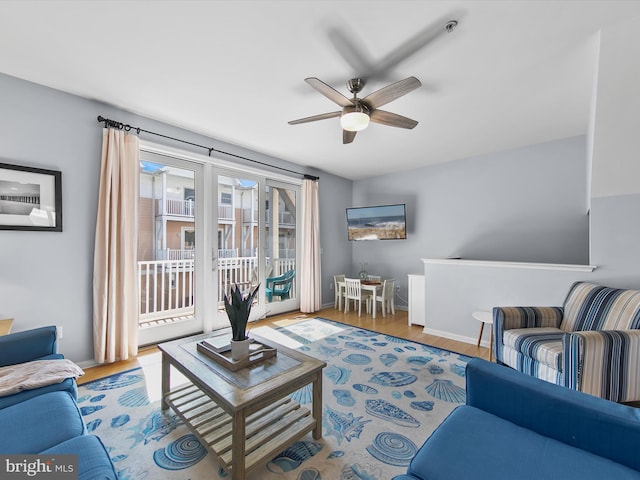 living area with wood finished floors, baseboards, and ceiling fan