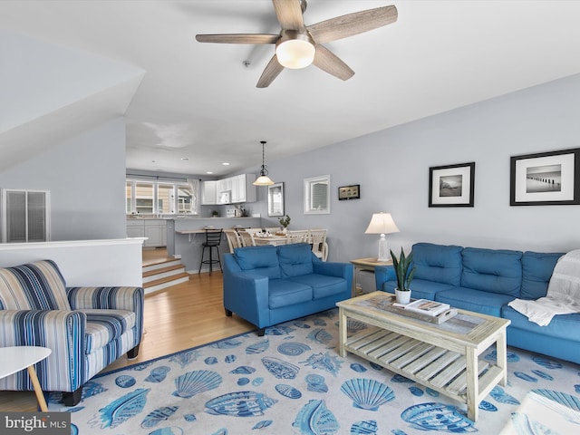 living room with light wood-style floors, visible vents, and ceiling fan