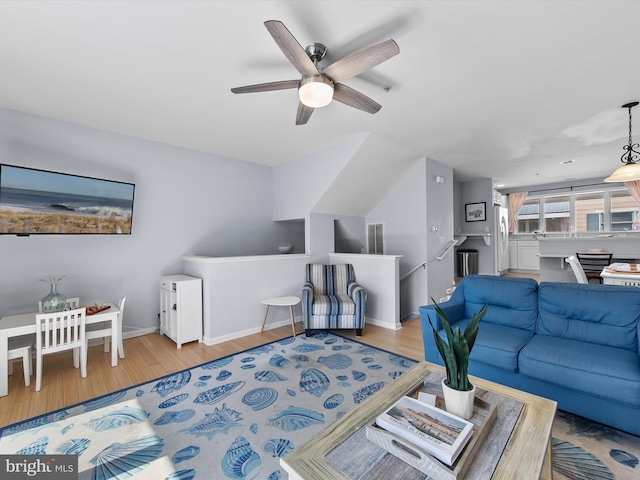 living room with a ceiling fan, baseboards, and wood finished floors